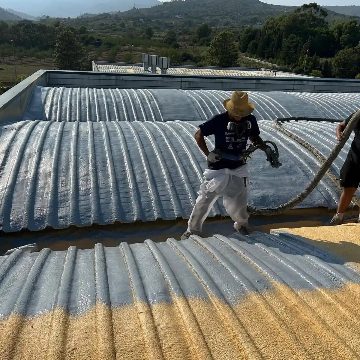 Two applicators spraying the membrane across the roof, Tarragona