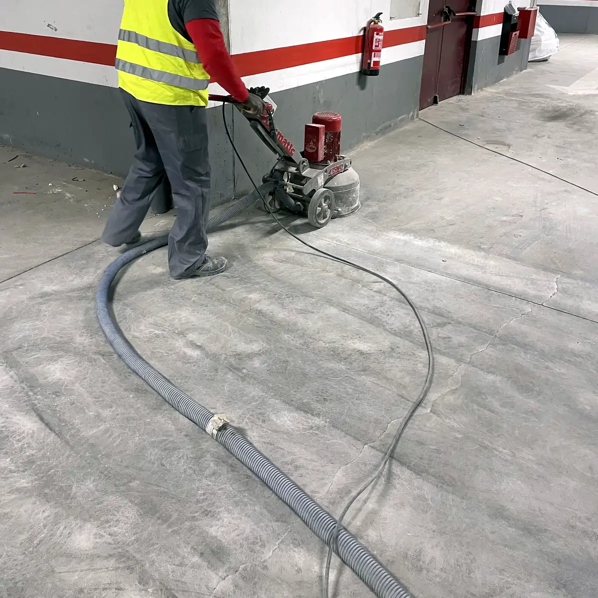 Operator grinding the concrete slab with a dust hose, Madrid Operator grinding the concrete slab with a dust hose, Madrid