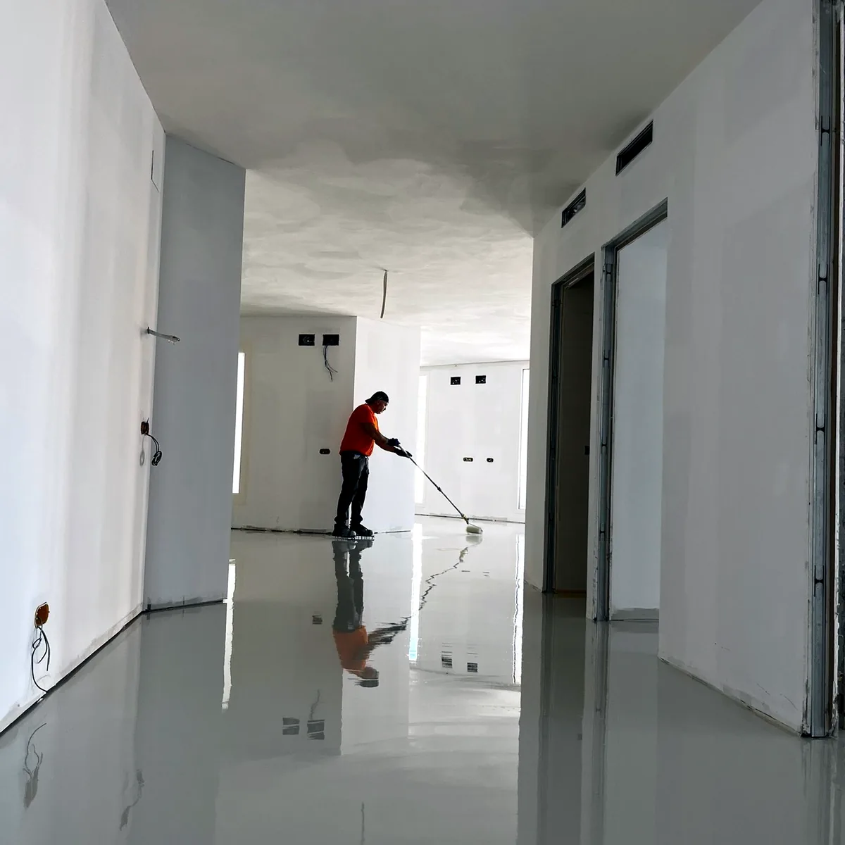 Worker rolling the coat at the end of a long white corridor