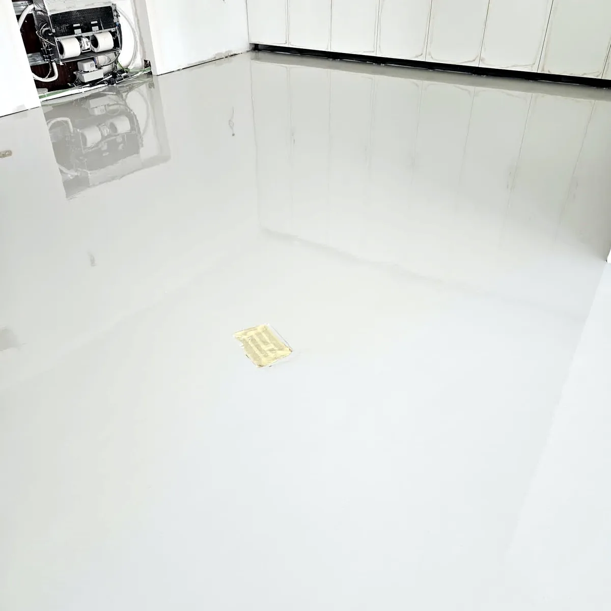 Glossy pale floor in a room with white wall units and a service box