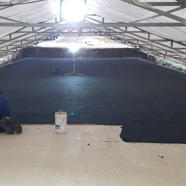 Two workers finishing the black granular layer against the pale border