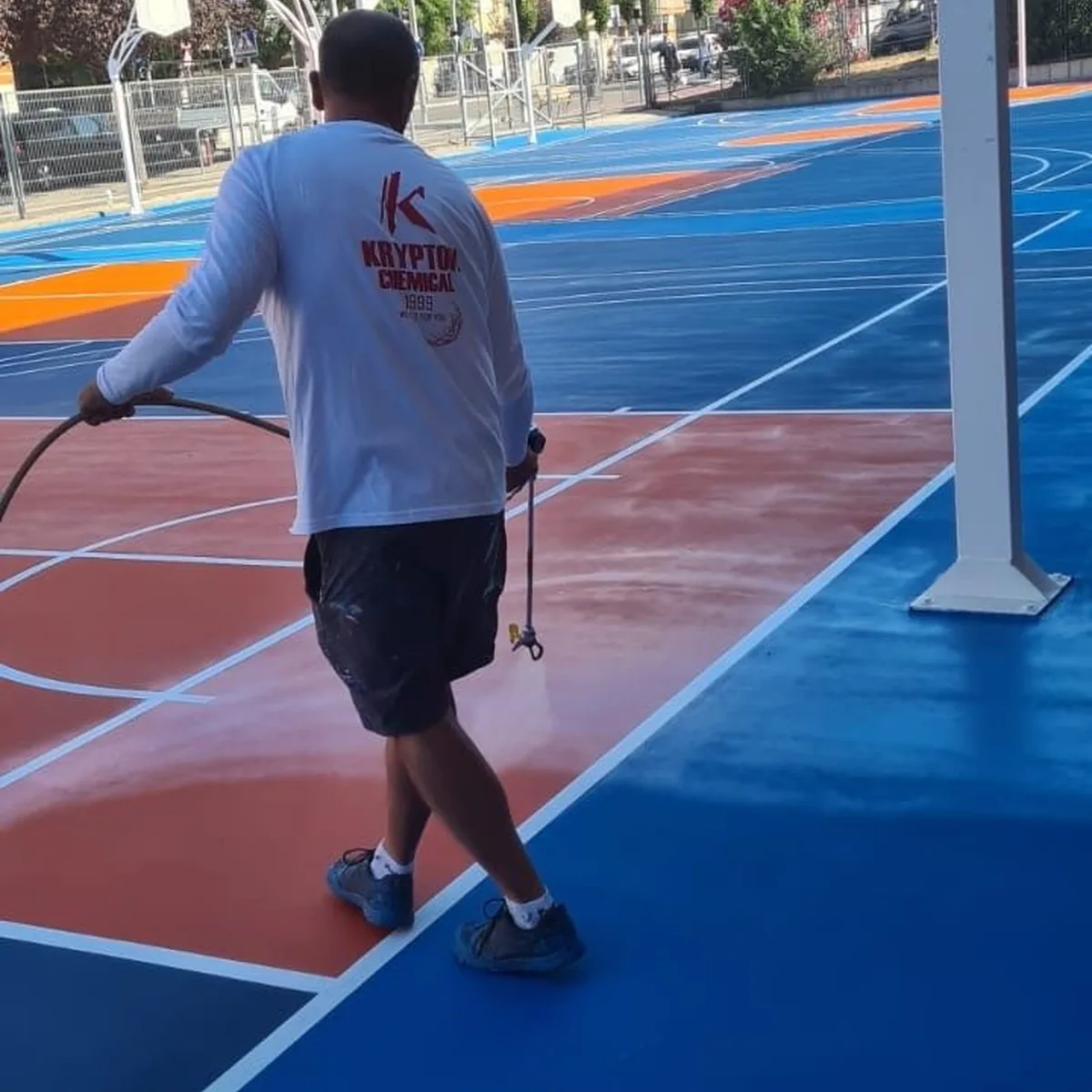 Applicator coating the court near a basketball hoop, Granollers