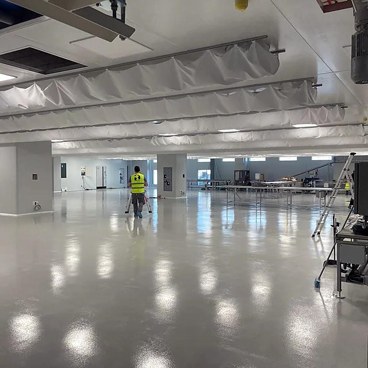 Glossy light grey floor across a wide production hall, Polinyà