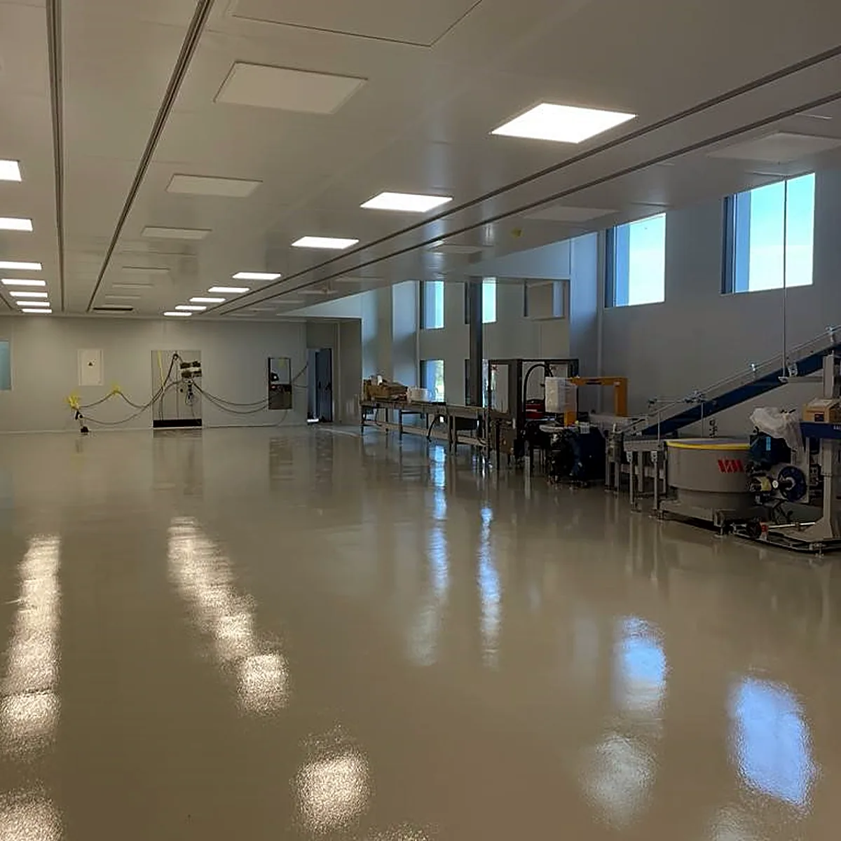 Grey floor beside a production line and a row of windows
