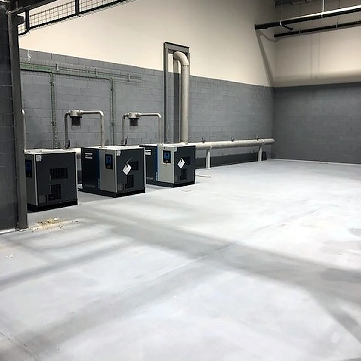 Machinery room corner with pipes rising above the coated floor Machinery room corner with pipes rising above the coated floor
