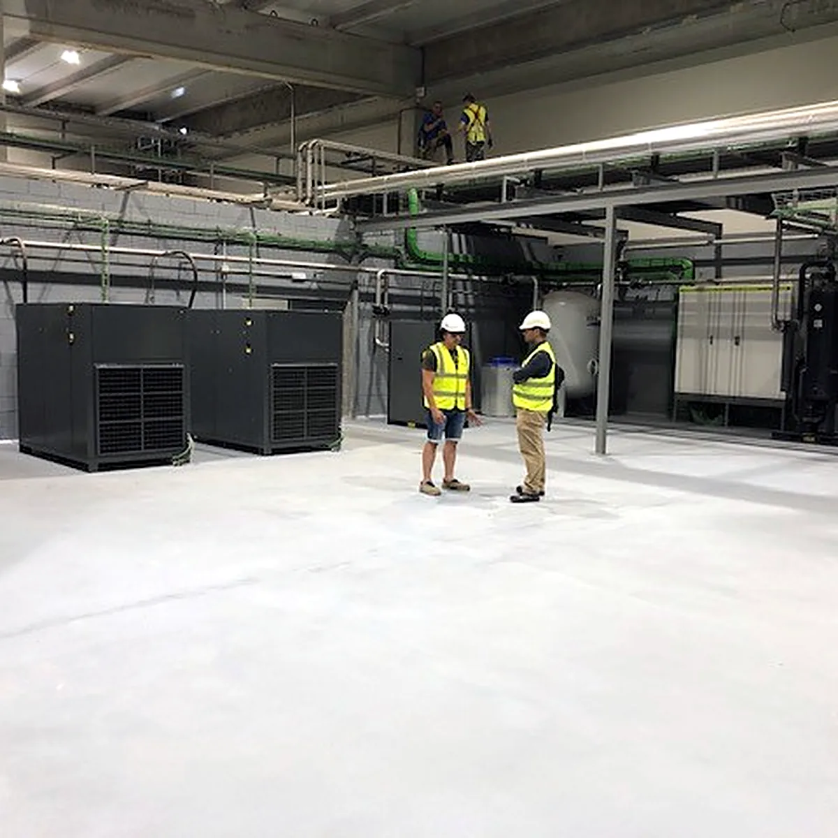 Two visitors inspecting the finished floor near the equipment units Two visitors inspecting the finished floor near the equipment units