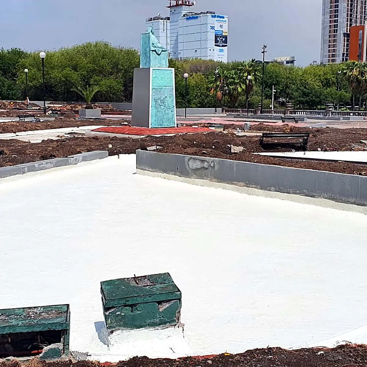 Jardinera ancha revestida en blanco con armarios de servicio verdes y torres al fondo Jardinera ancha revestida en blanco con armarios de servicio verdes y torres al fondo