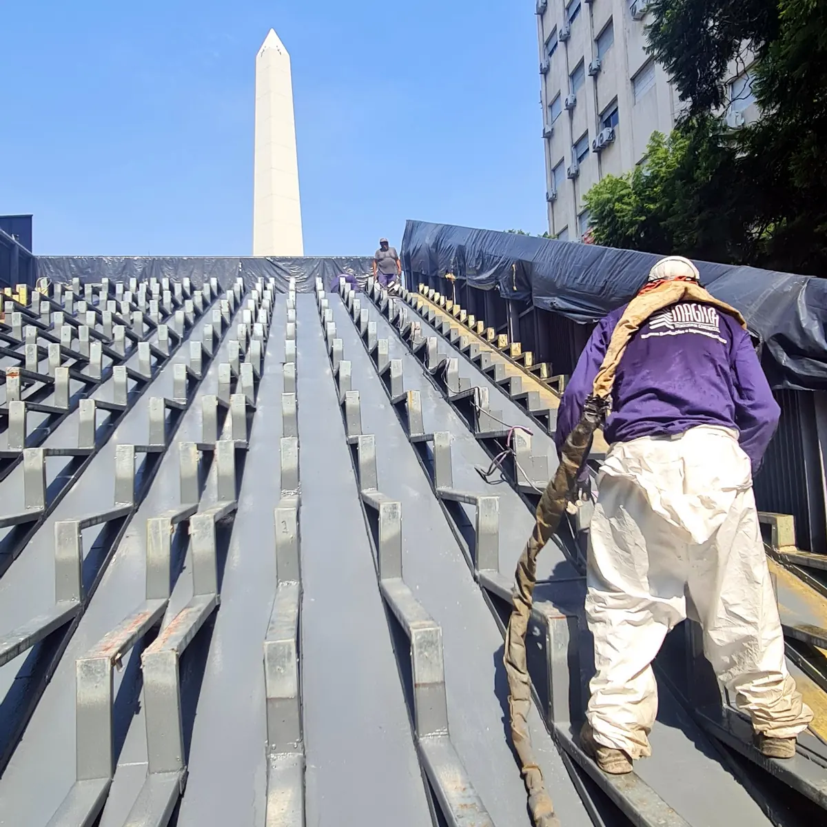 Applicator with the spray hose walking up the coated roof slope, Buenos Aires