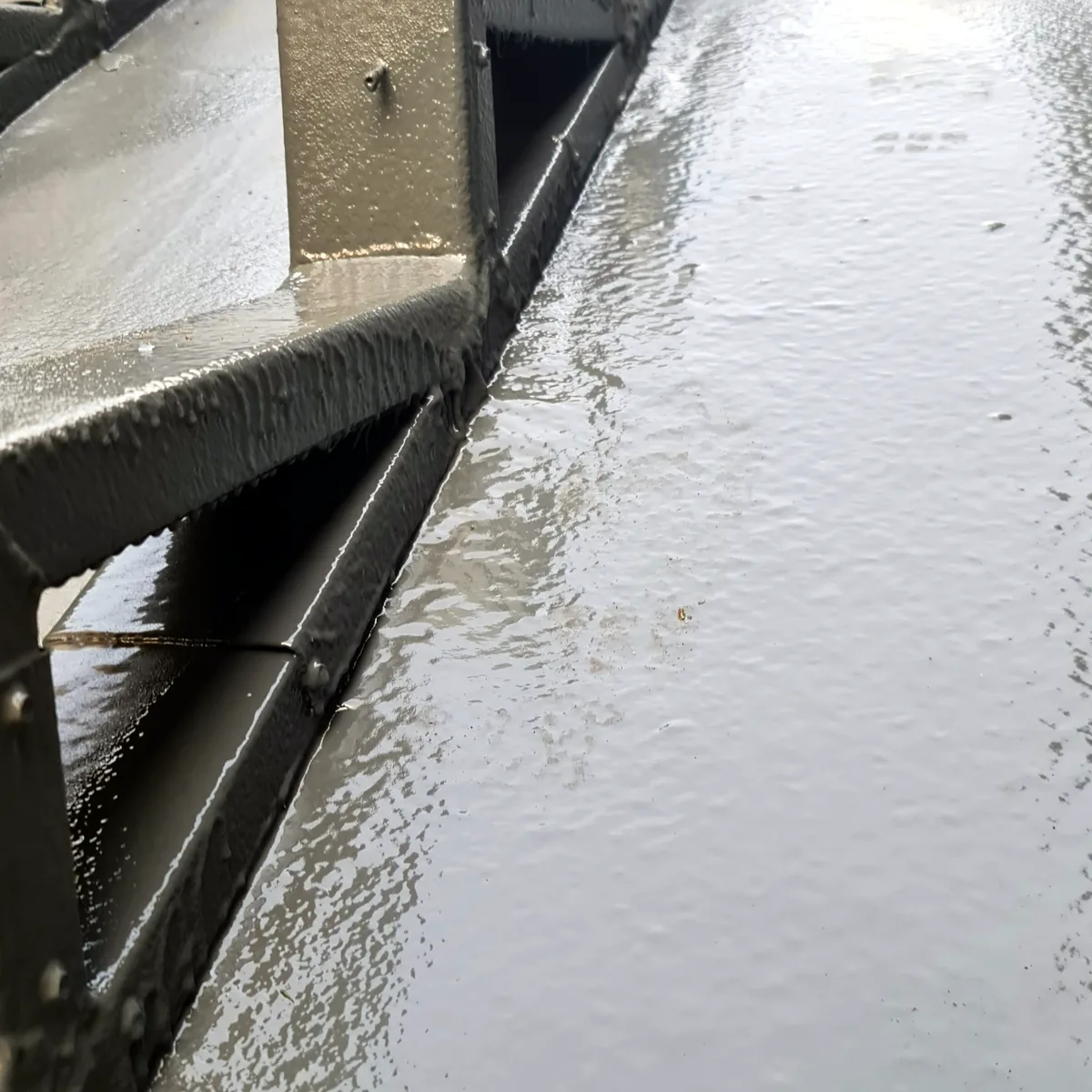 Glossy finished membrane in a roof channel next to a steel frame, police centre roof