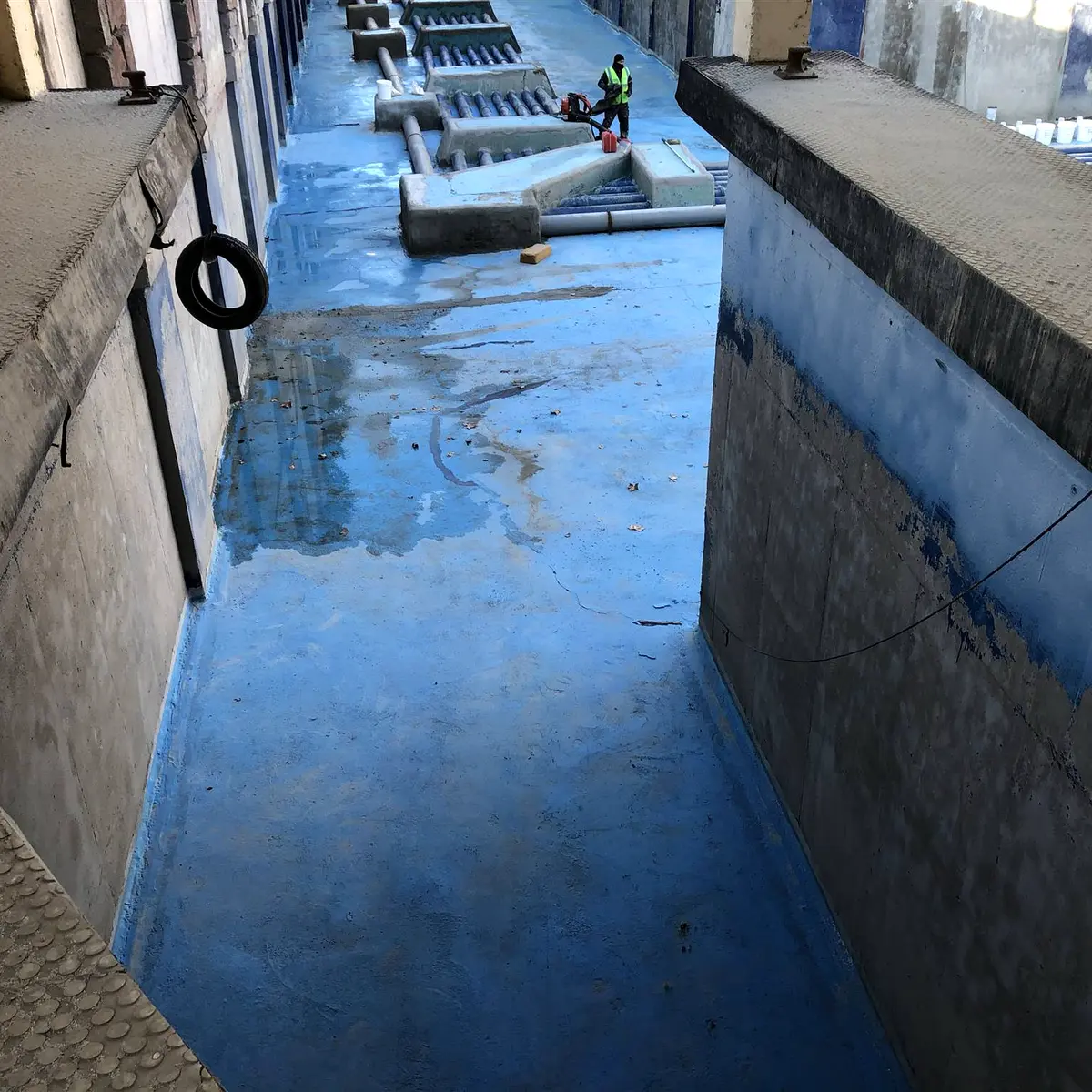 Blue-coated channel floor between bare concrete walls, Parque Warner Madrid