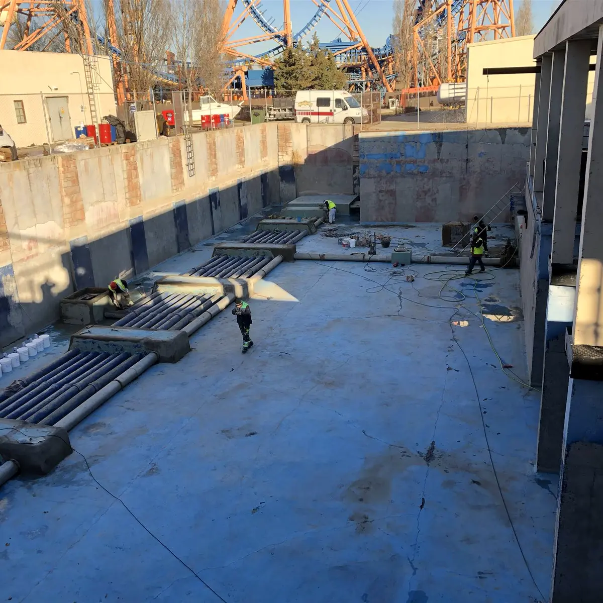 Crew preparing a drained concrete basin with pipe manifolds, Parque Warner Madrid