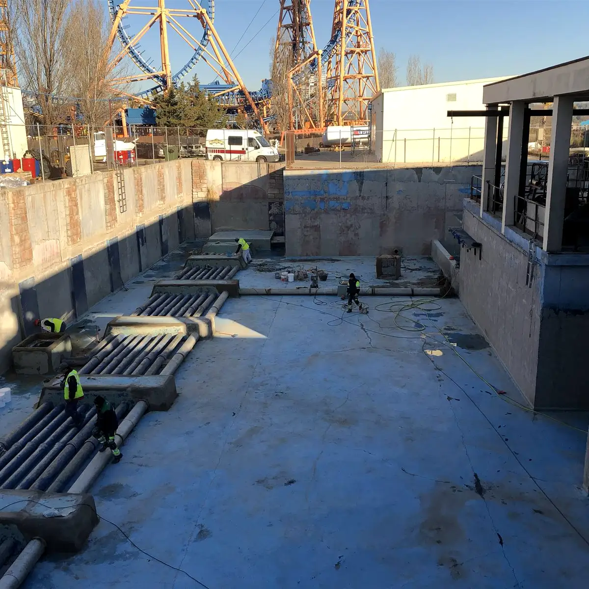 Drained concrete basin with rides in the background, Parque Warner Madrid
