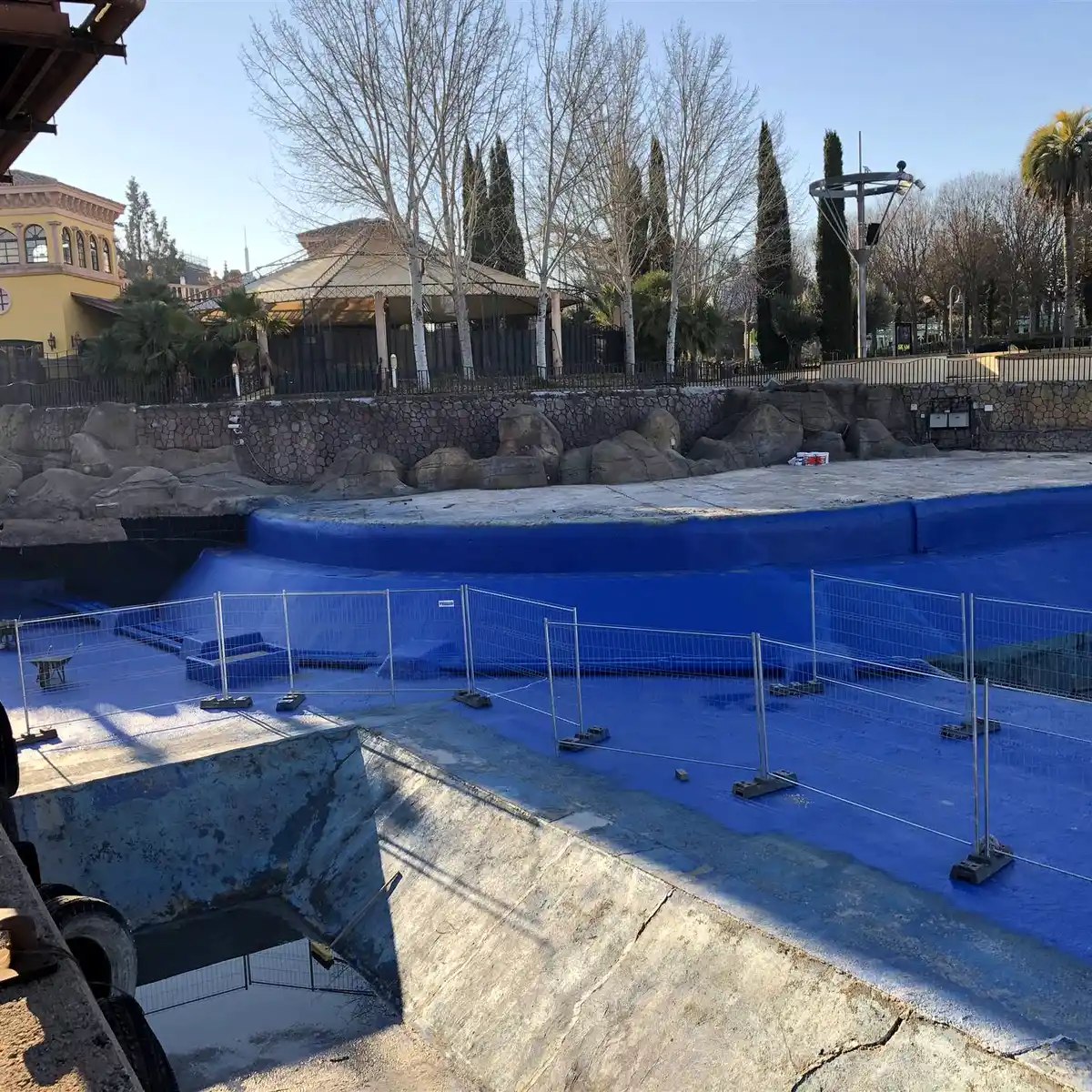 Blue-lined basin edge behind temporary site fencing, Parque Warner Madrid