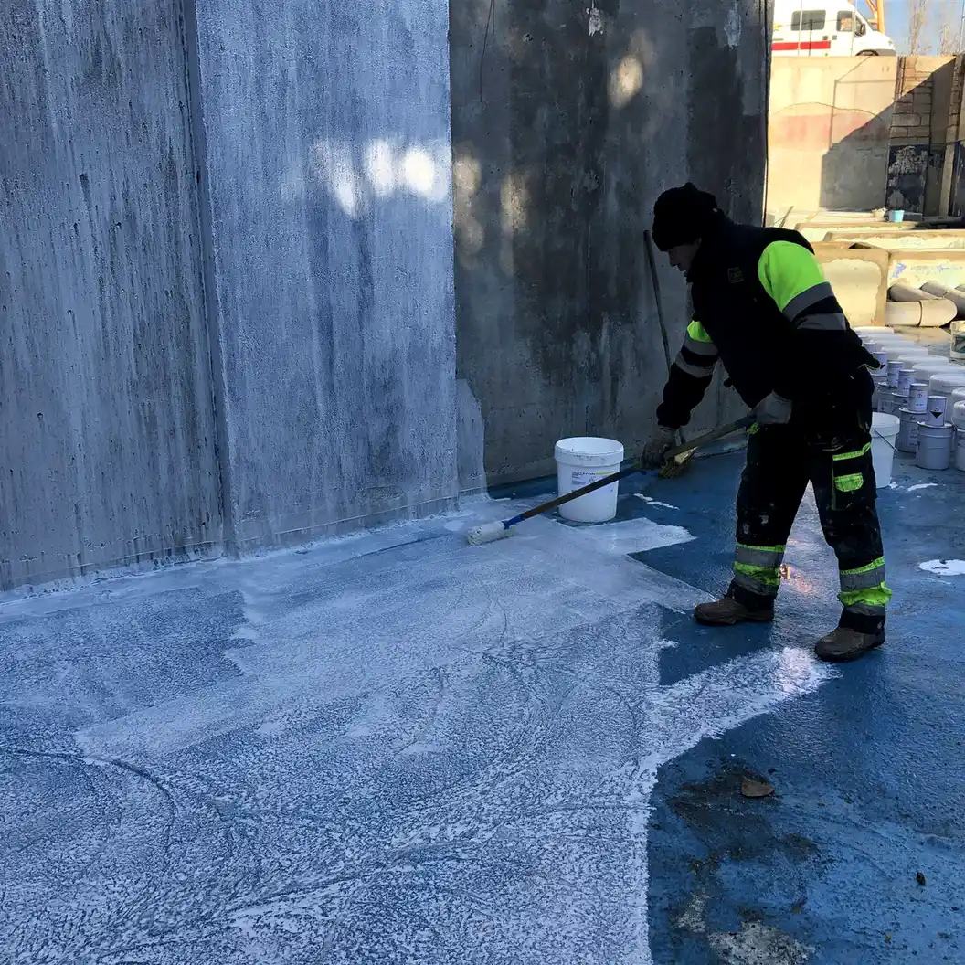 Worker rolling primer on a concrete lake wall, Parque Warner Madrid
