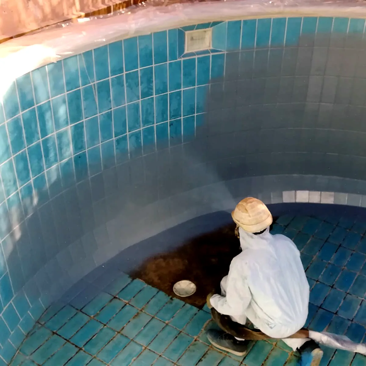 Applicator working on the tiled pool floor and walls in Almansa Applicator working on the tiled pool floor and walls in Almansa