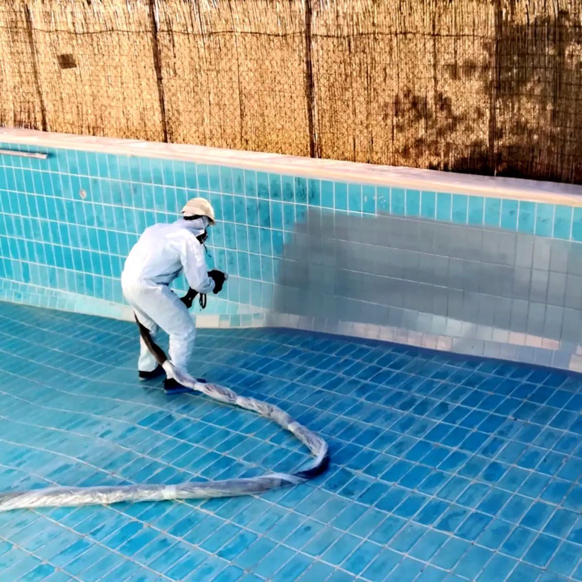 Applicator coating the tiled pool wall during the first layer, Almansa Applicator coating the tiled pool wall during the first layer, Almansa