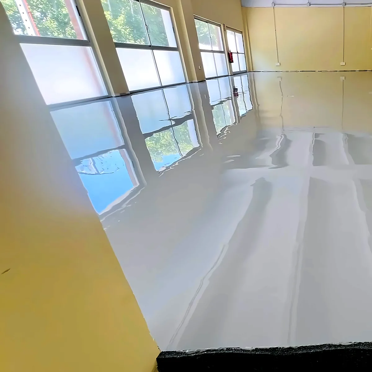 Pavimento de resina terminado junto al frente de ventanas, aparcamiento privado en Badajoz