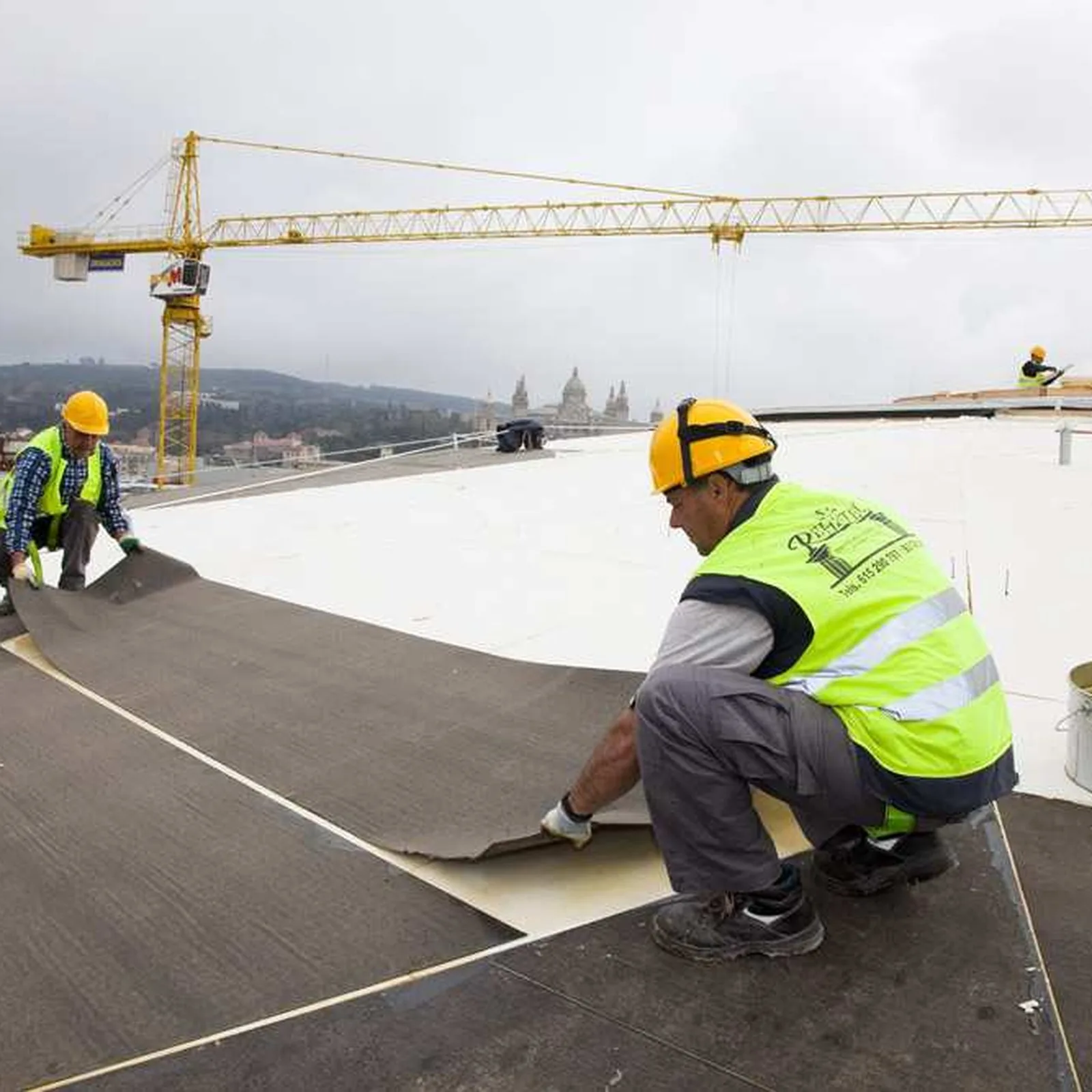 Worker rolling out Rayston Vel carrier felt over the insulation on the Las Arenas dome