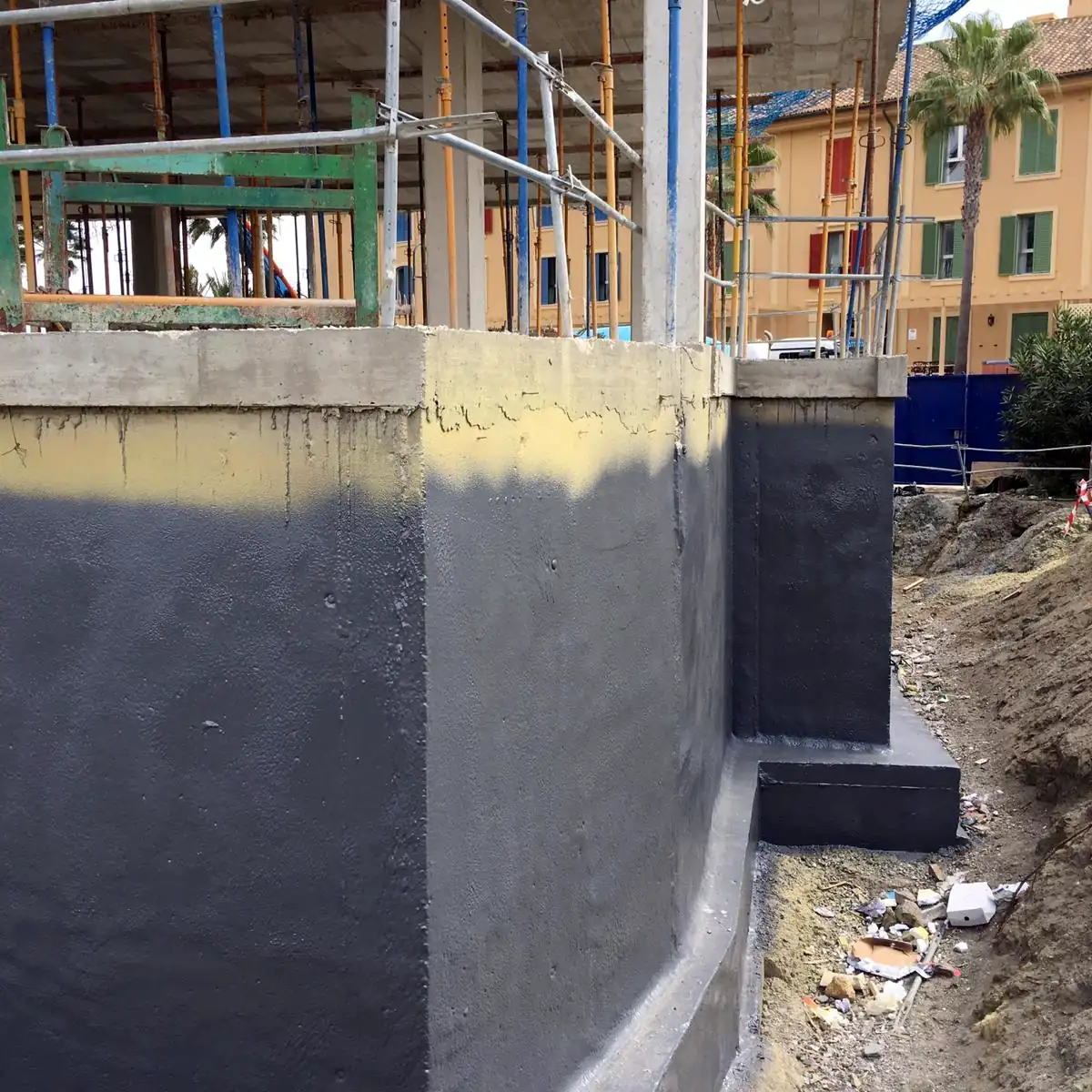 Finished grey radon barrier on a foundation wall in front of the apartment blocks