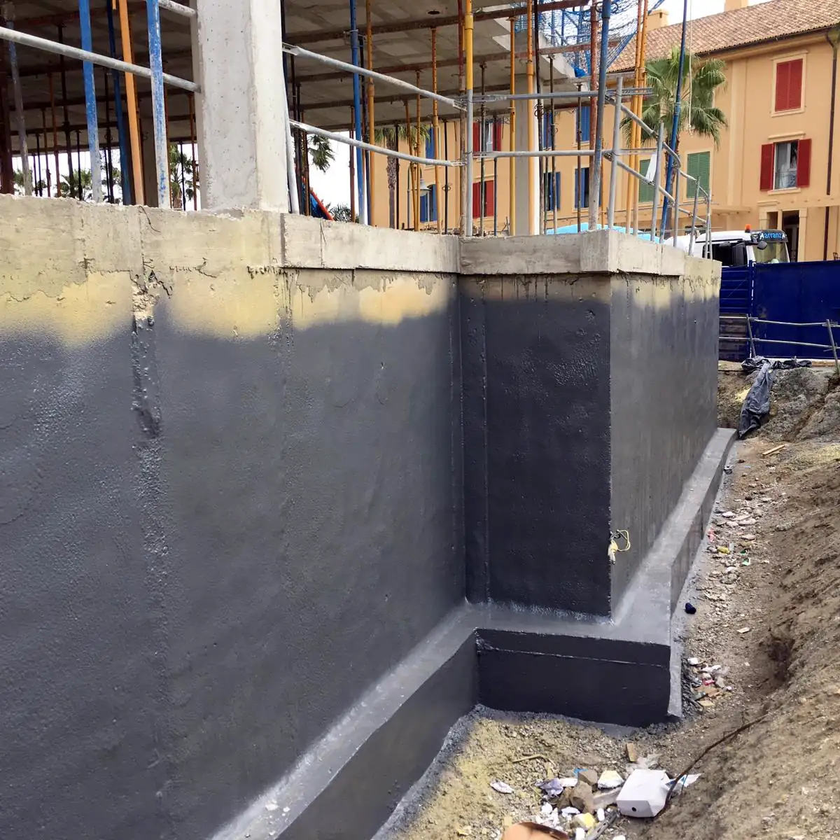 Grey Rayston Spray D50 membrane wrapping a foundation wall corner and footing