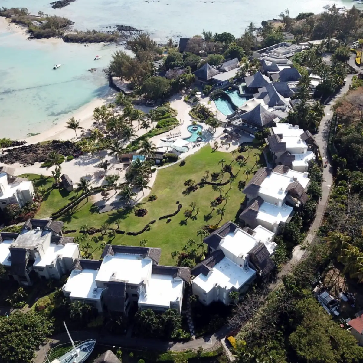 Aerial view of white cool roofs on resort bungalows beside the lagoon in Mauritius