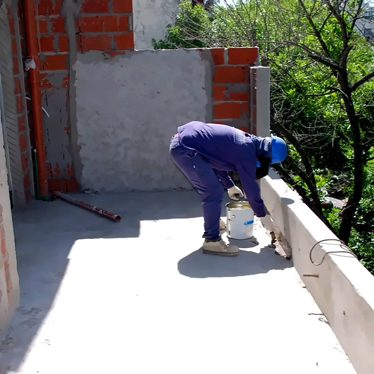Worker preparing the concrete roof deck before waterproofing, residential building in Buenos Aires