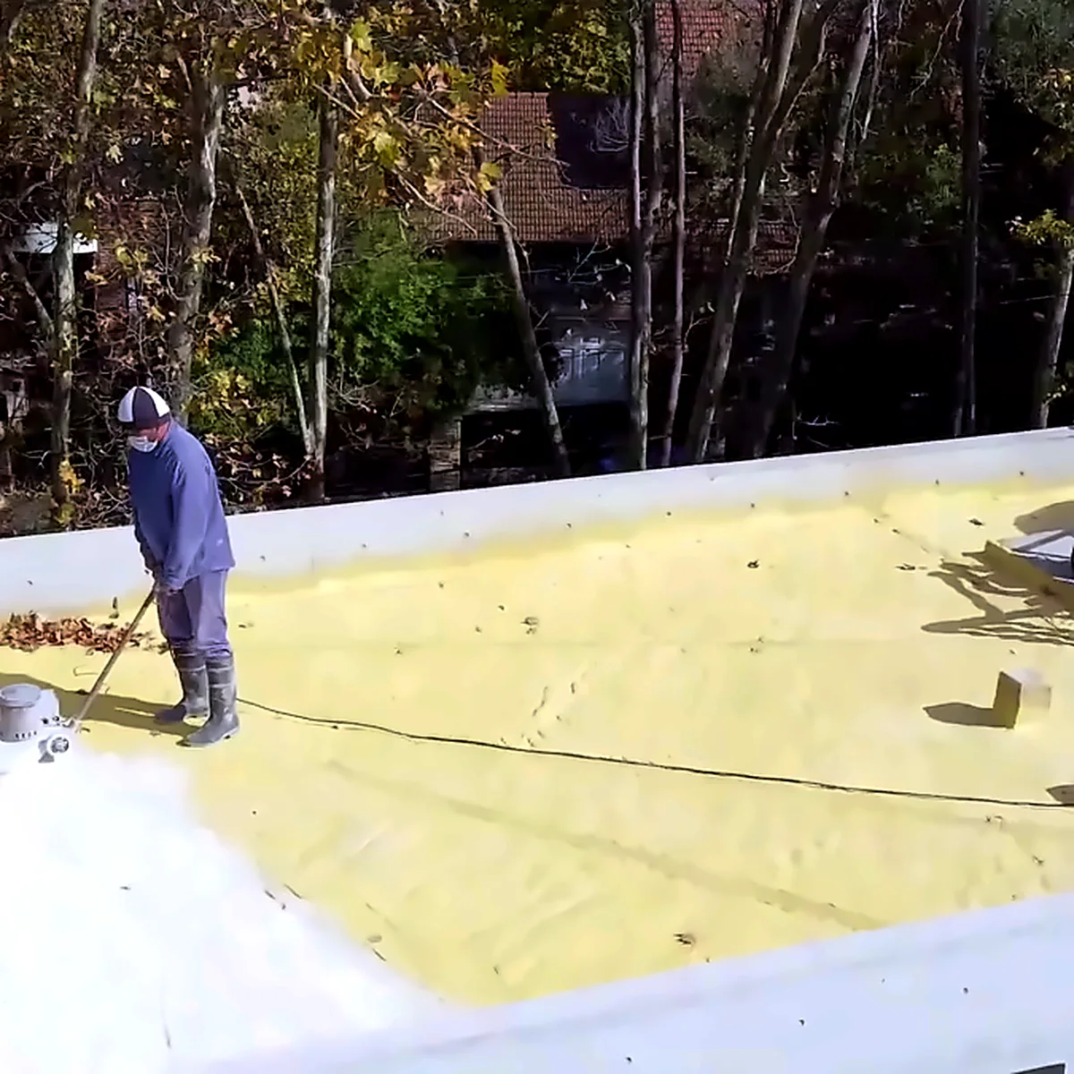 Applicator on the yellow polyurethane foam insulation of a flat roof in San Isidro, Argentina Applicator on the yellow polyurethane foam insulation of a flat roof in San Isidro, Argentina