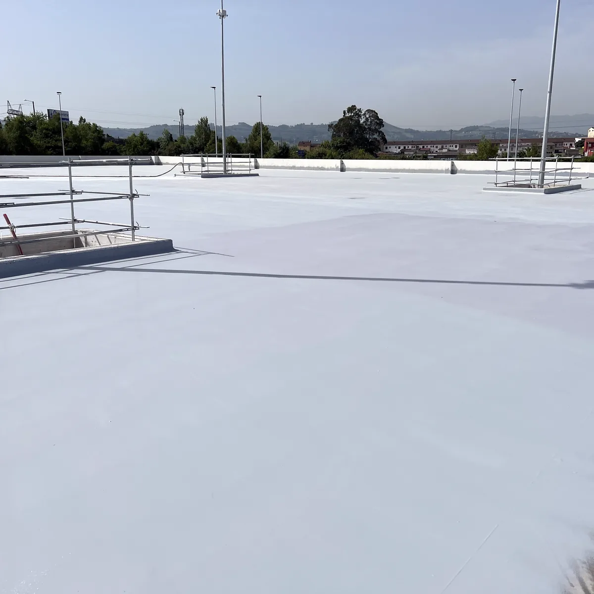 Rooftop parking waterproofing in La Línea at the deck edge, beside a low railing