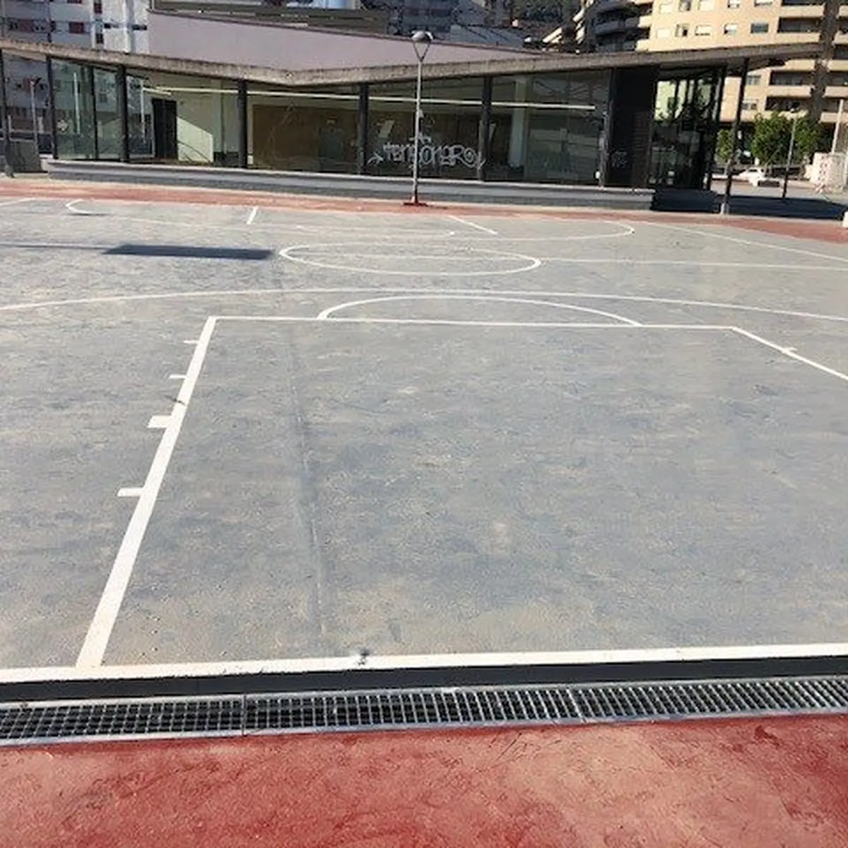 Faded grey court with drainage channel before coating, Montcada i Reixac