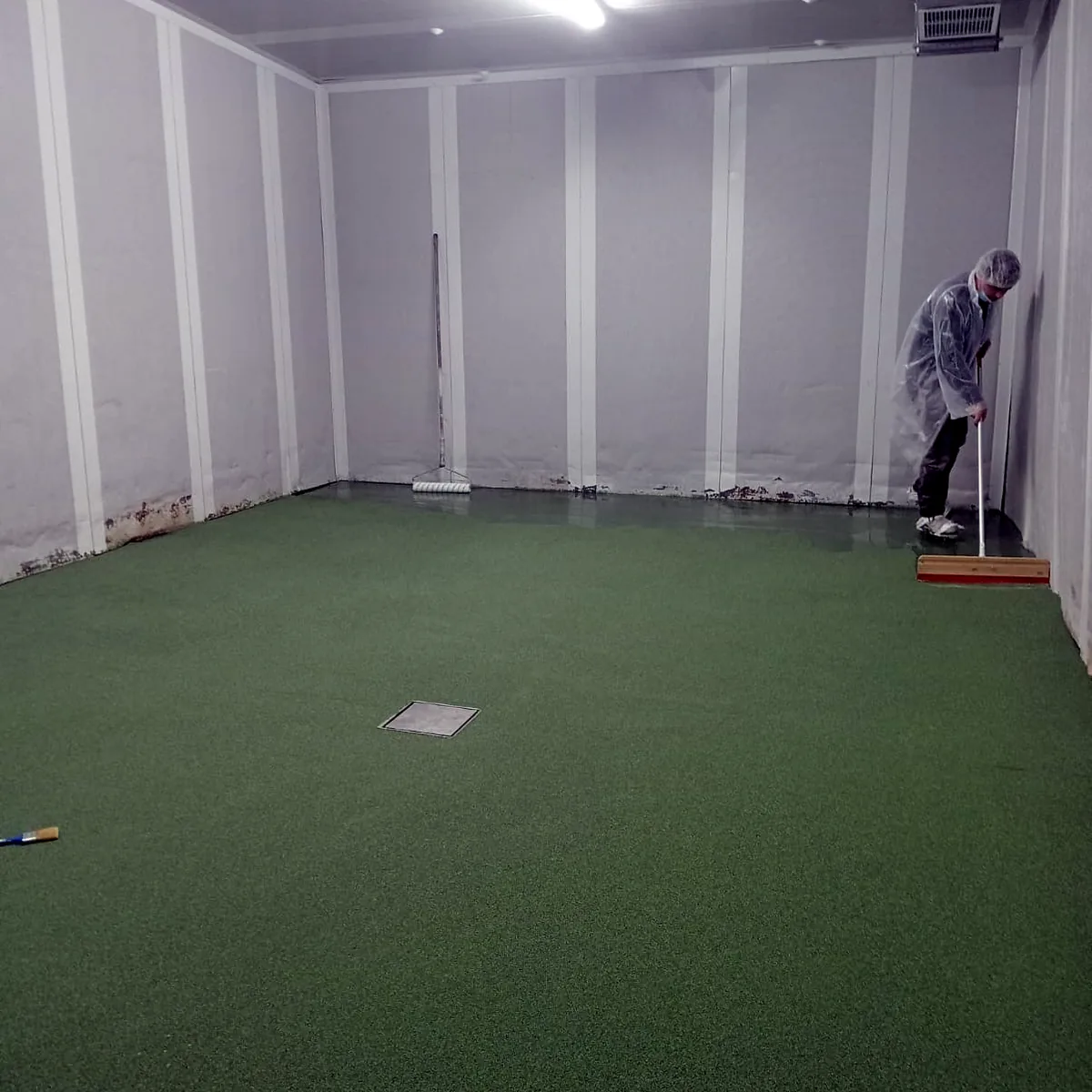 Applicator working on the green floor at the back of the room Applicator working on the green floor at the back of the room