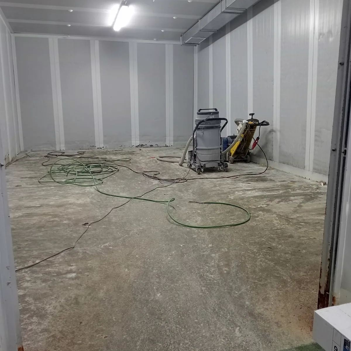 Old floor with a grinder and hoses before the works Old floor with a grinder and hoses before the works