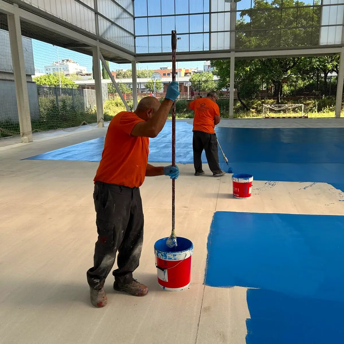Second worker rolling the blue field in the background