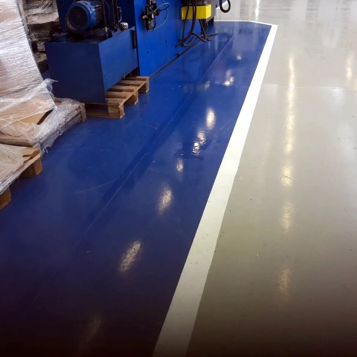 Blue zone with a white line beside a blue machine on pallets