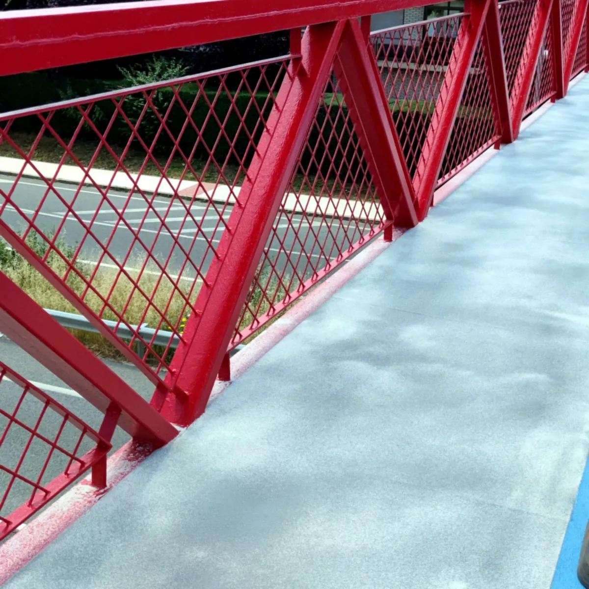 Steel walkway protection Madrid: red railings and grey deck after coating