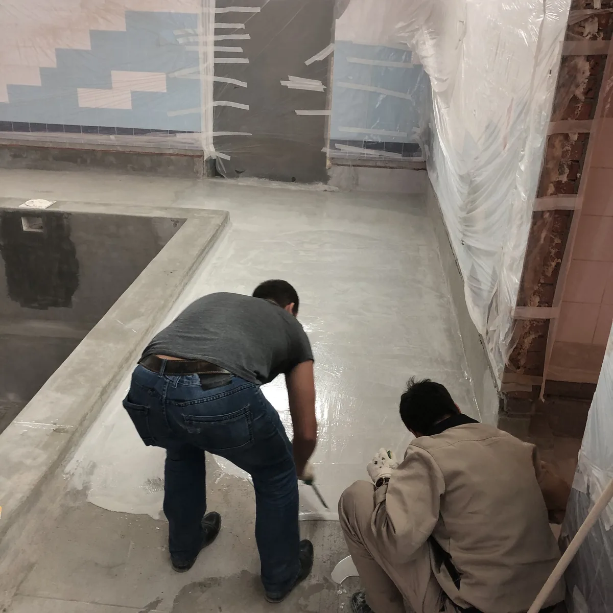 Two workers levelling the wall-to-floor junction, Nizhny Novgorod