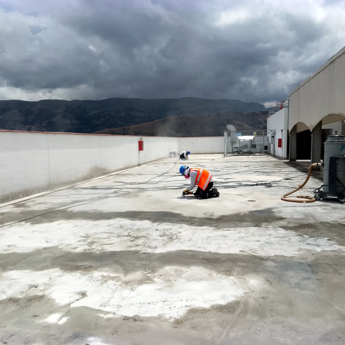 Operario sobre el forjado parcialmente diamantado con las salas técnicas al fondo, cubierta UTP