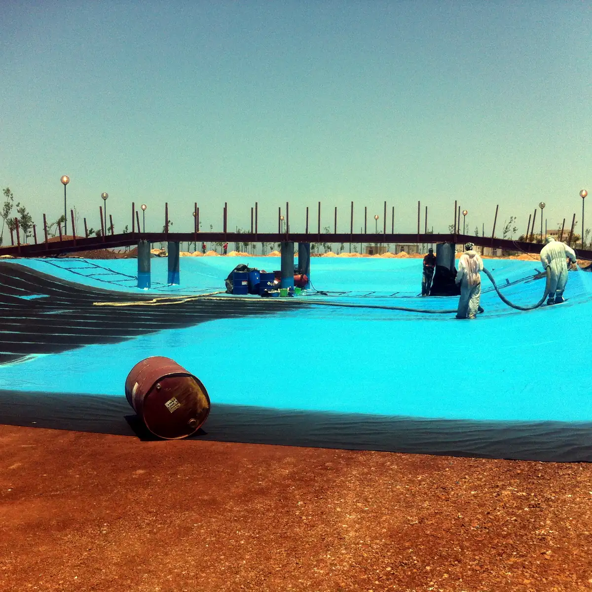 Operators and a fabric roll on the half-sprayed lake base