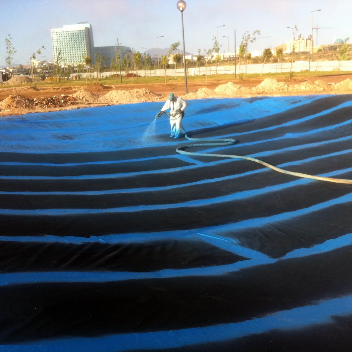 Black Geomax Spray NMDC geotextile laid over the lake slopes, Algeria