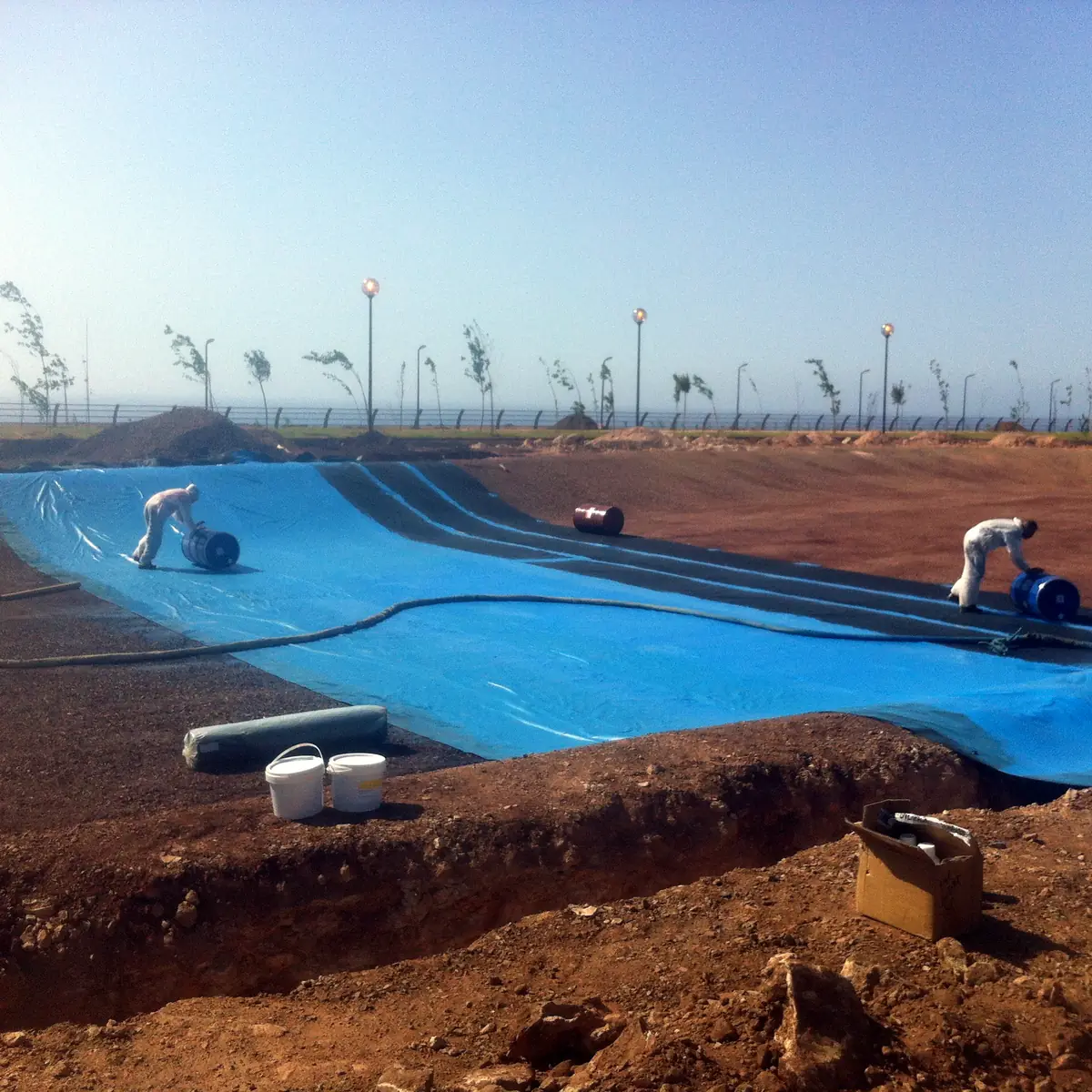 Spray hose and operators on the lake slope, Algeria