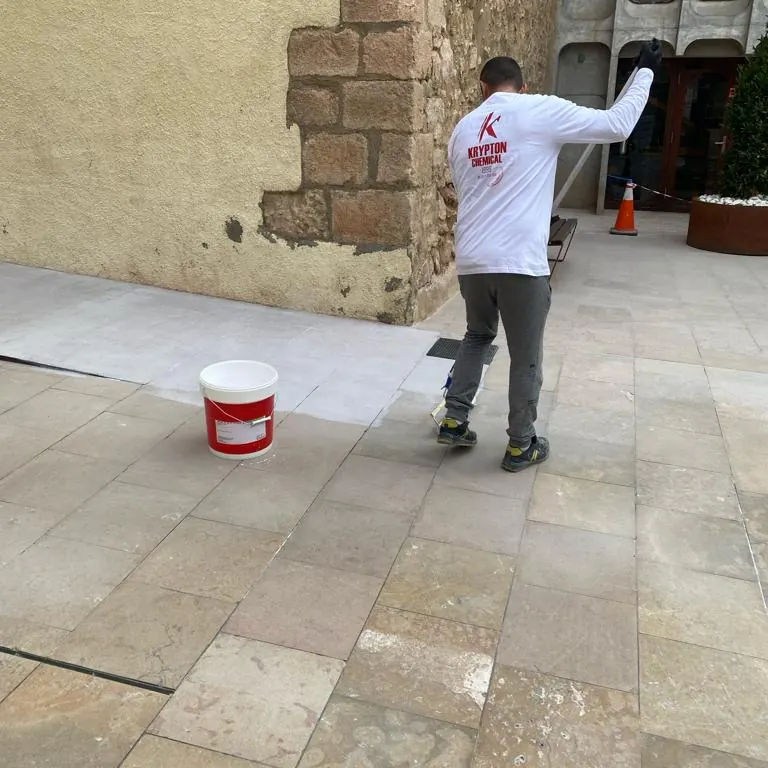 Operario extendiendo a rodillo la capa transparente sobre la piedra