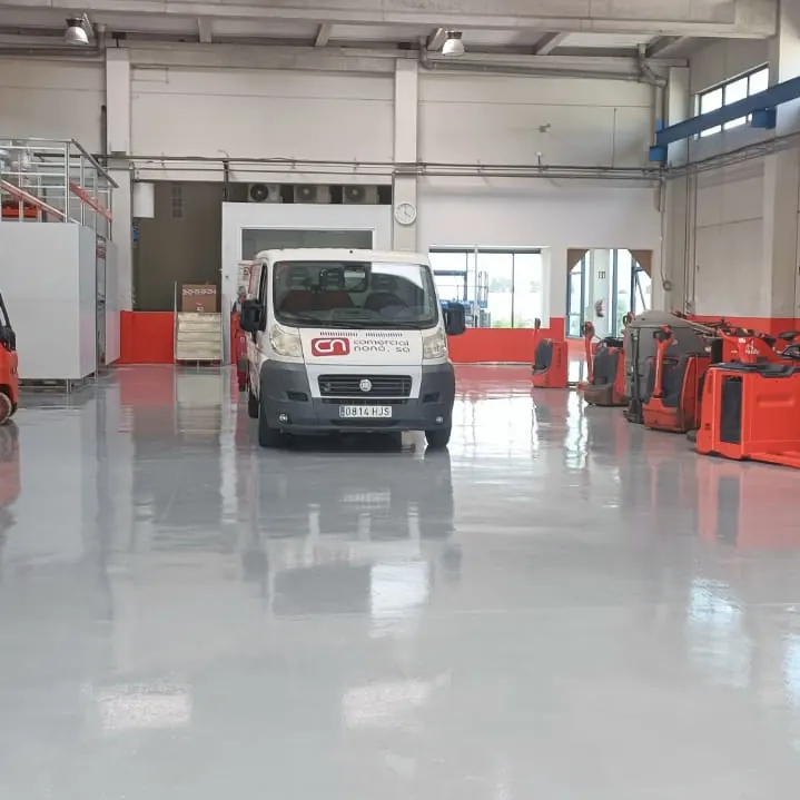 Red lifting trucks and a van on the grey floor