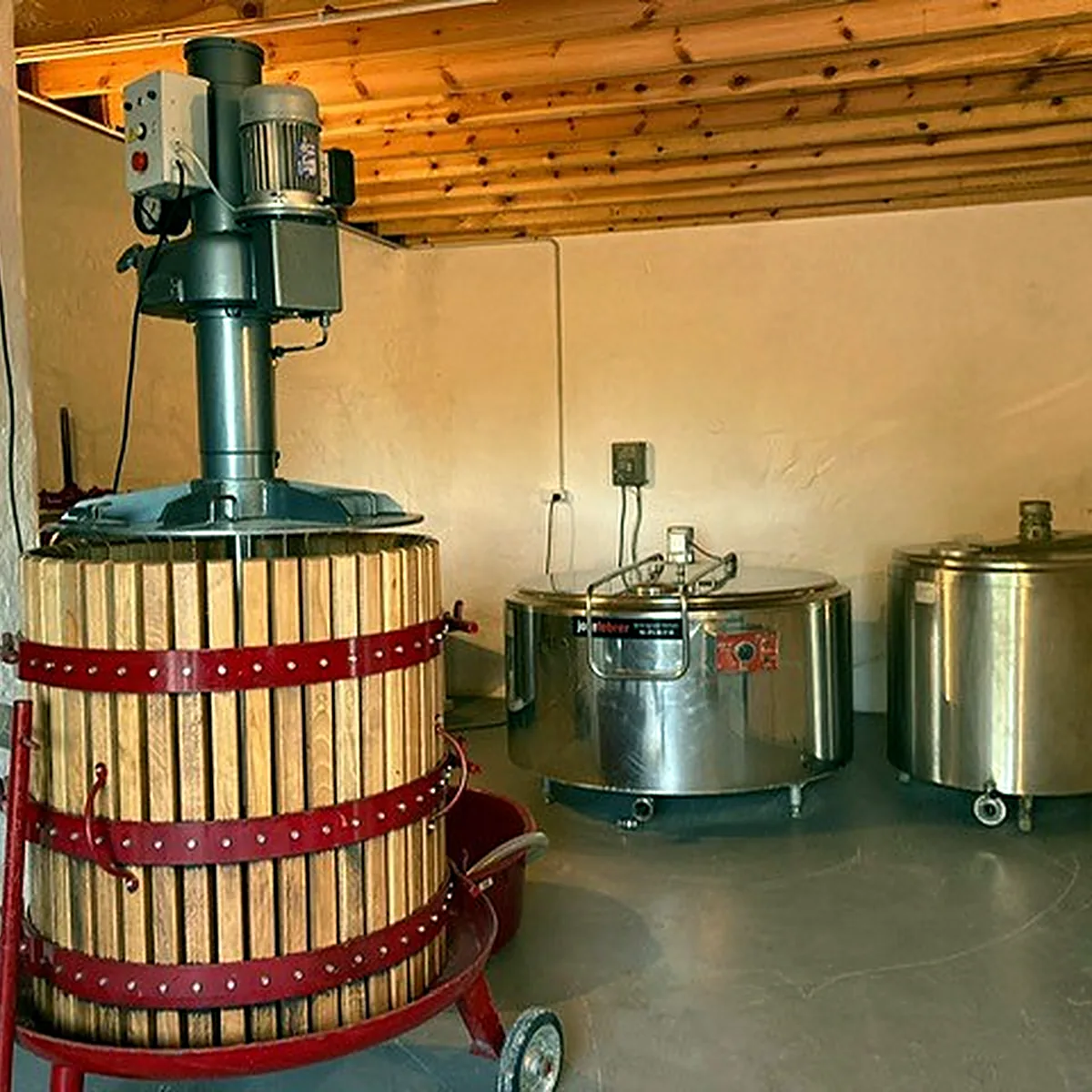 Wooden press and small steel vats under a timber ceiling Wooden press and small steel vats under a timber ceiling