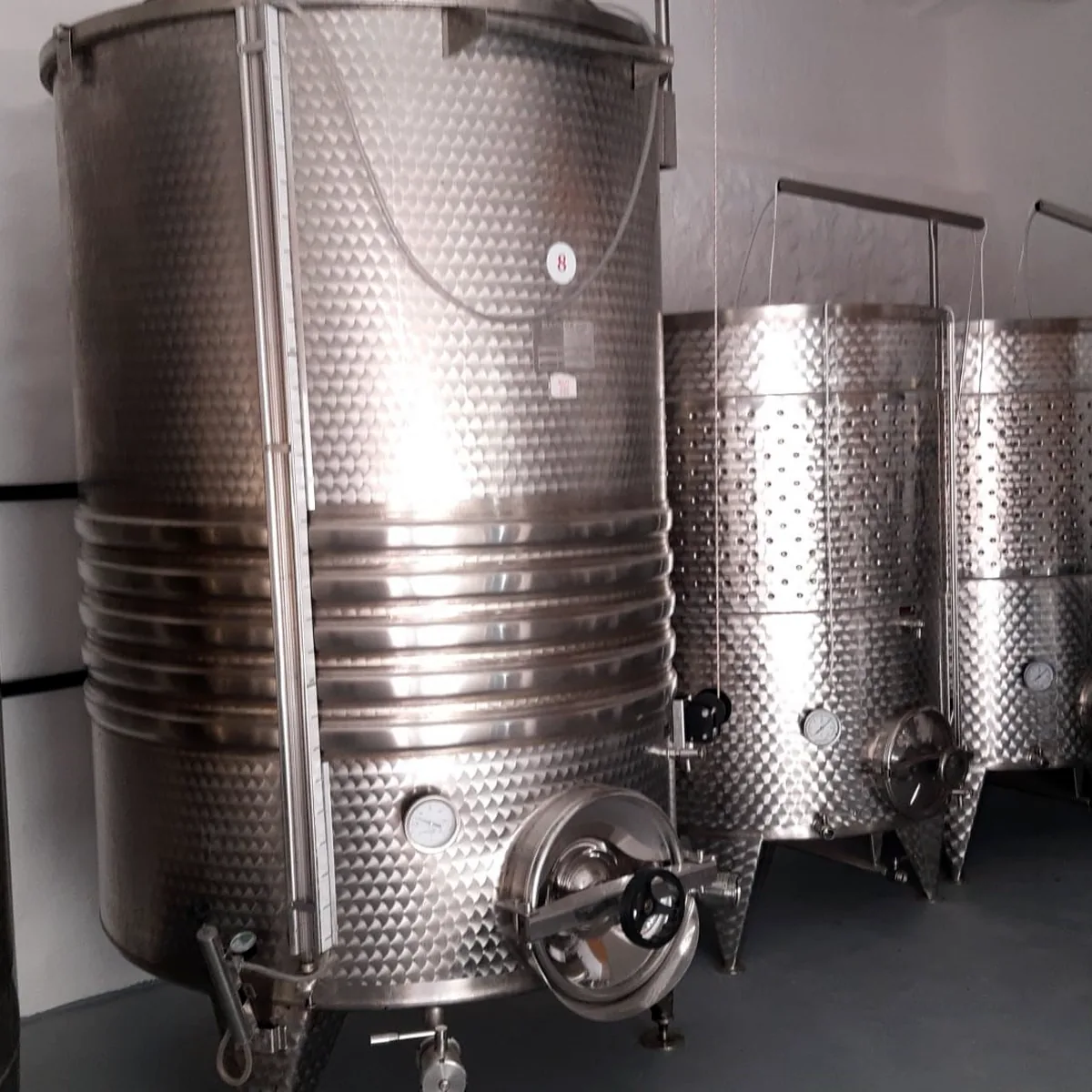 Row of stainless steel wine tanks on the coated floor, Maó Row of stainless steel wine tanks on the coated floor, Maó